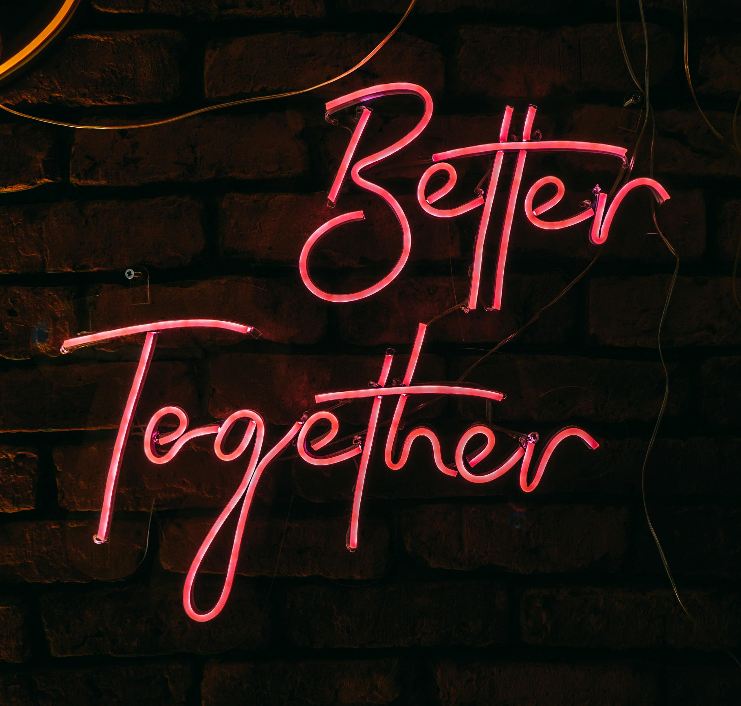 Illuminated neon sign 'Better Together' glowing against a rustic brick wall in Istanbul.